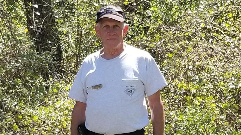 a man in a volunteer uniform stands in front of trees