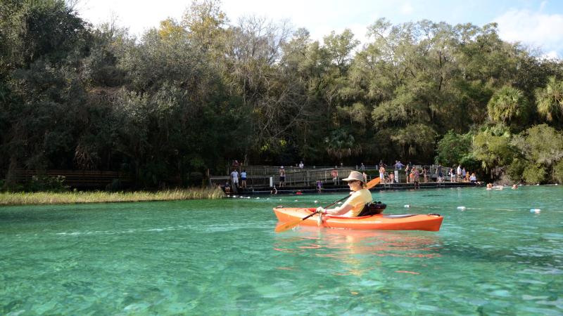 A person paddles an orange kayak at Rainbow Springs State Park.