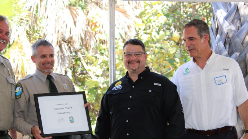 Paul Rice presents the award to Robert Barker with Brian Fugate and Jose Romano.