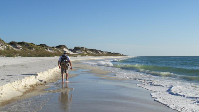 A faraway view of someone walking on the beach.