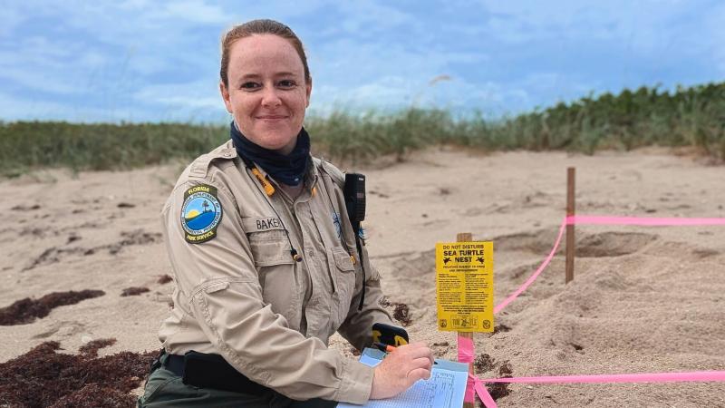 A smiling park ranger taking an inventory of a sea turtle nest. 