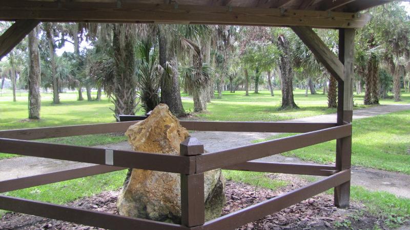 A large limestone rock sits behind a fence enclosure.