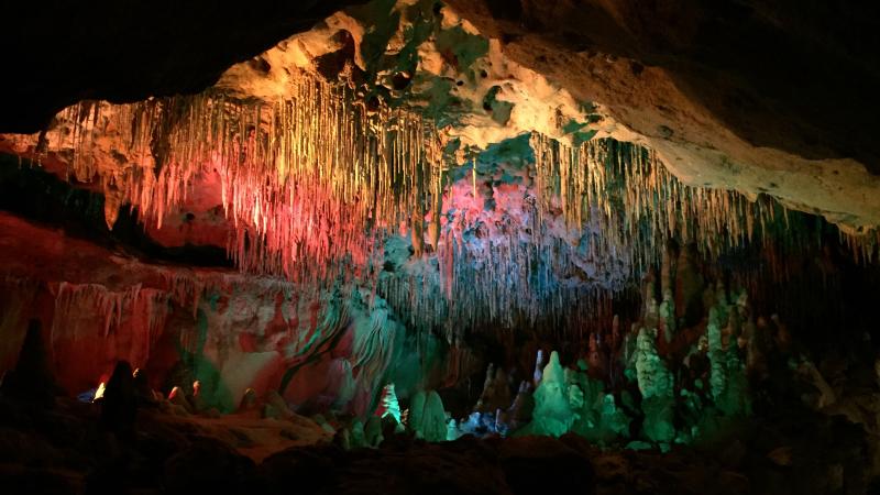 View of inside the caverns with colorful lights accenting the natural stalagtites