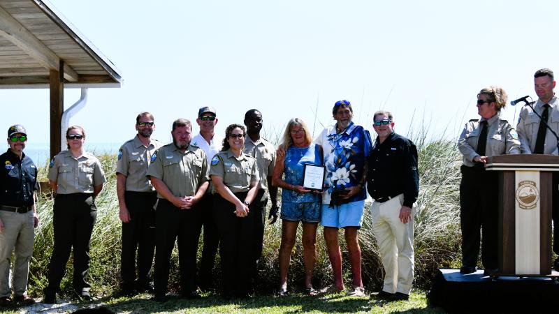volunteers hold their plaque award while surrounded by park staff