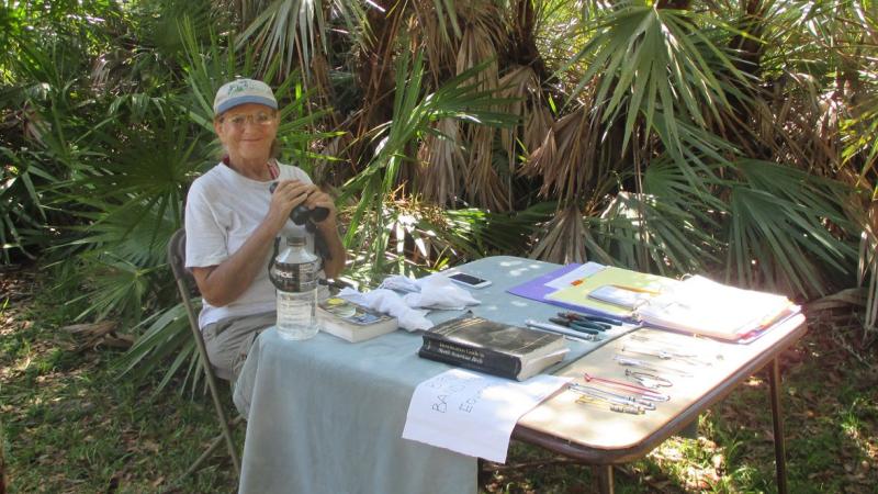 Volunteer Meret Wilson with her bird banding station and binoculars in hand