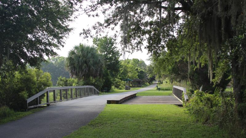 A bridge crosses a small ditch along a green pathway.