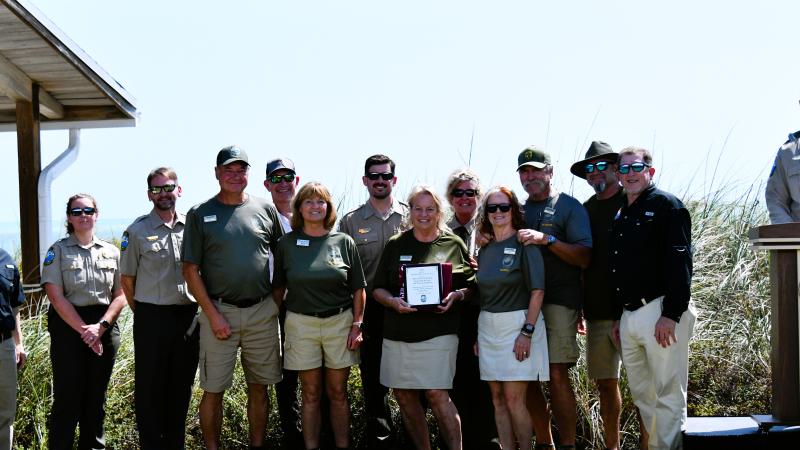 volunteers stand with plaque award surrounded by park staff