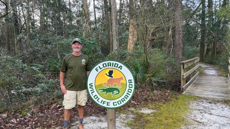 Jim Quyle in front of the Florida Wildlife Corridoor photo.