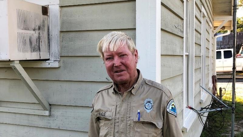 a man in uniform with white hair stands next to a building smiling