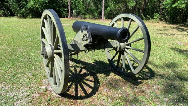 a large cannon on wheels stands on the grass
