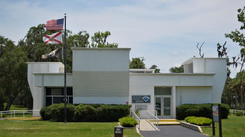 a large white building with irregular shapes, flying the state and American flags.