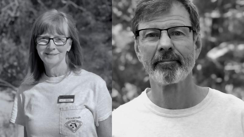 a woman and man in glasses and volunteer uniforms smile