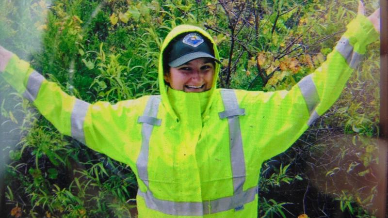 a woman in a raincoat waves her arms