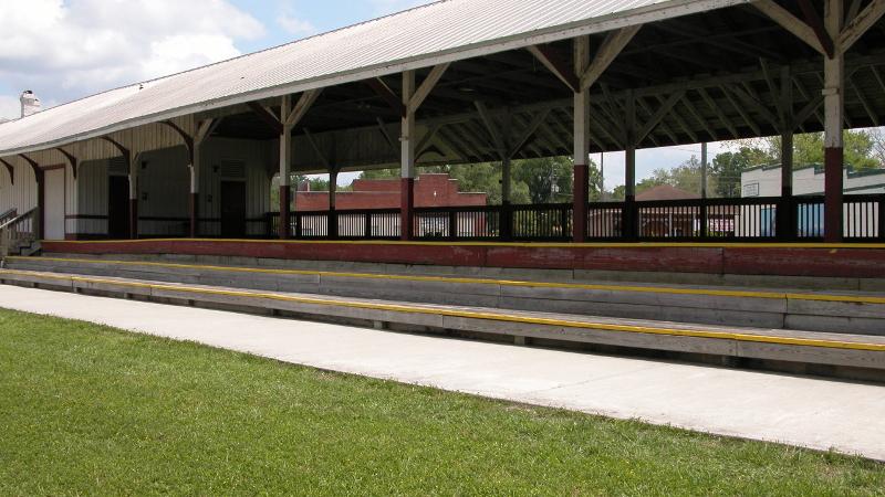 a long roofed train platform next to a paved trail