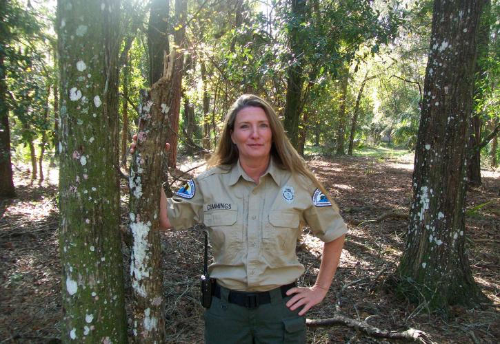 Park Ranger Jane Cummings in the forest smiling at the camera