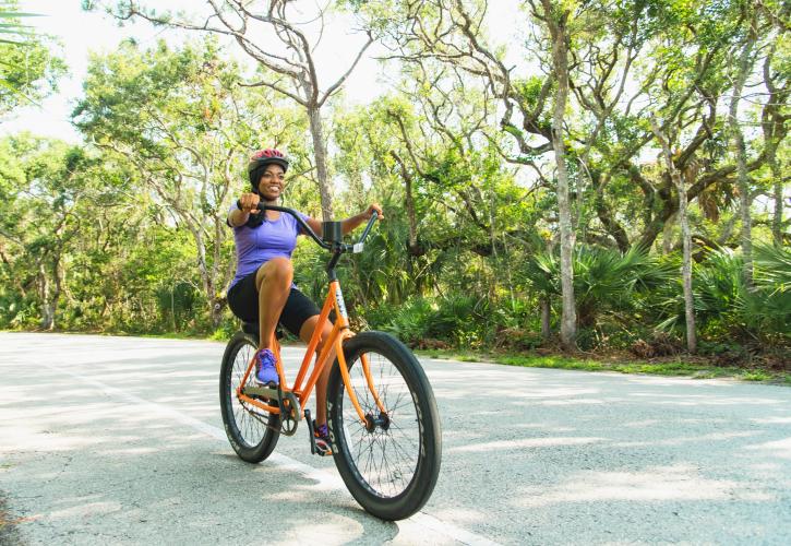 A person riding an orange bicycle at Anastasia State Park.