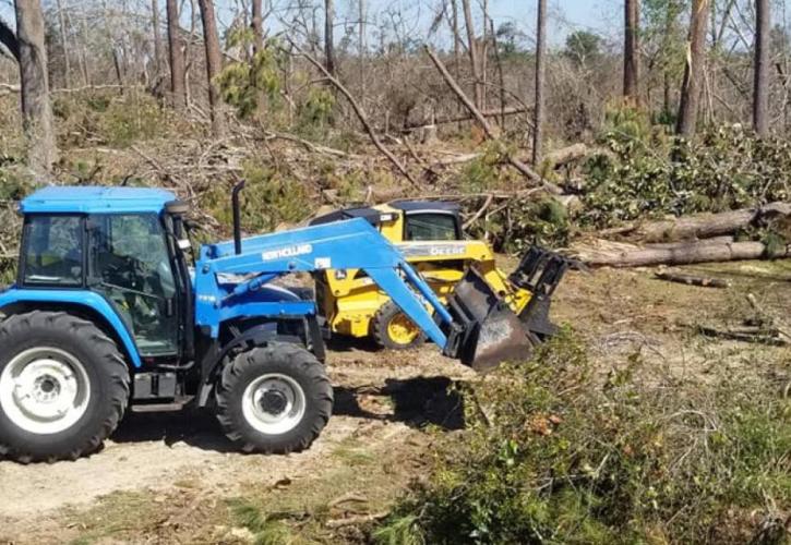 A view of a couple of bulldozers moving downed trees.