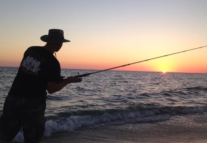 A man fishes at sunset.