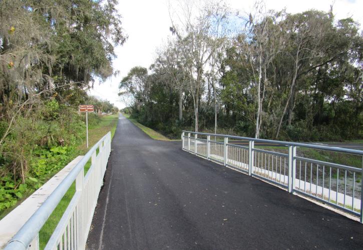 A paved trail with a bridge on either side. 