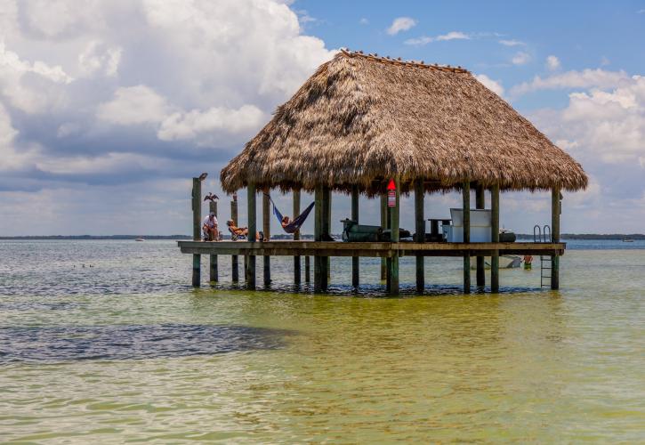 A view of a tiki style pavilion out in the middle of the water.