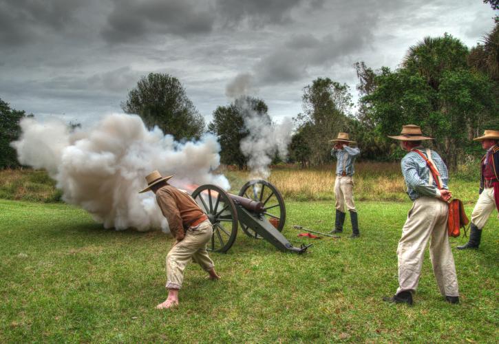 4 Reenactment actors standing around a cannonball firing 