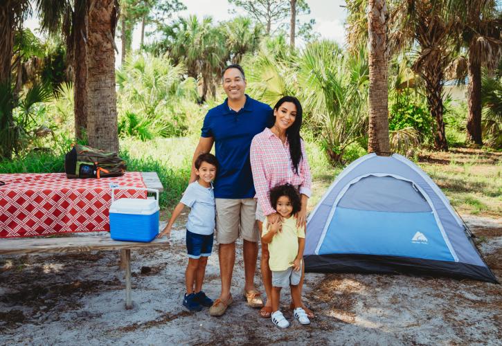 A family stands in front of their tent.