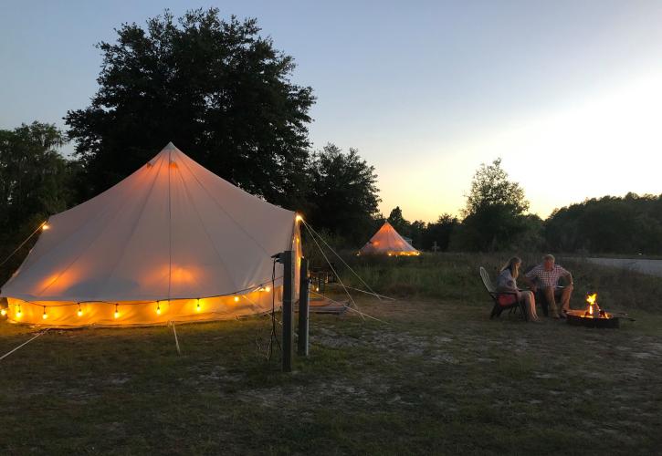 Couple around a campfire outside of their Care Free Camping luxury tent