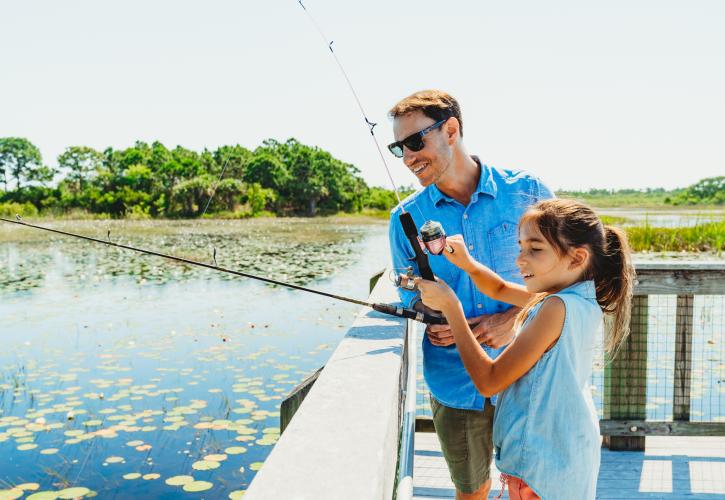 A man and child fish from a dock at Savannas Preserve State Park.