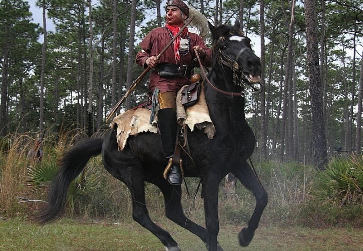 A Seminole reenactor riding a horse.