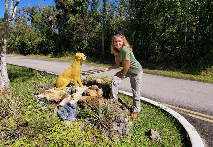 woman standing next to panther statue