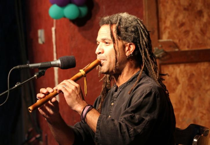 a man plays a native american flute into a microphone.