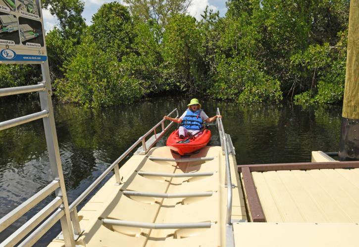 Woman entering canoe launch in a red kayak