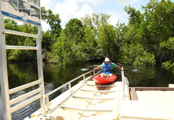 Man pulling up onto canoe launch in red kayak