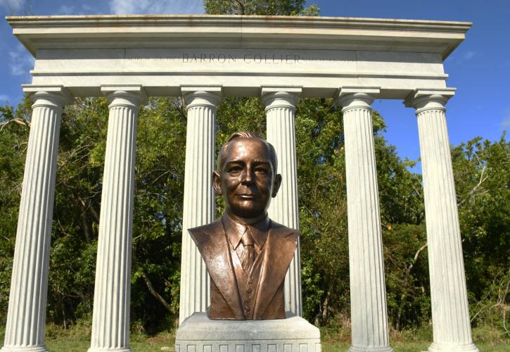 copper color bust of Barron Gift Collier in front of marble column memorial