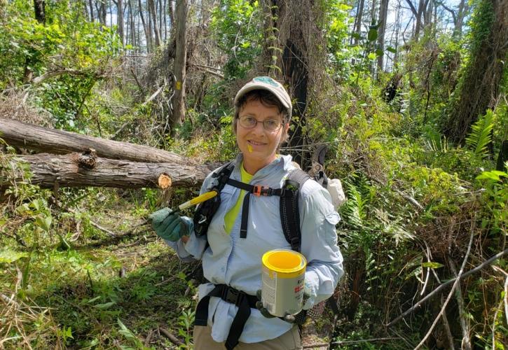 Woman holding yellow paint can standing in a forest