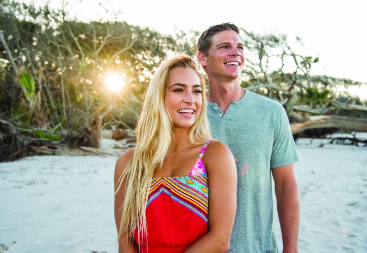 Couple posing for picture by driftwood