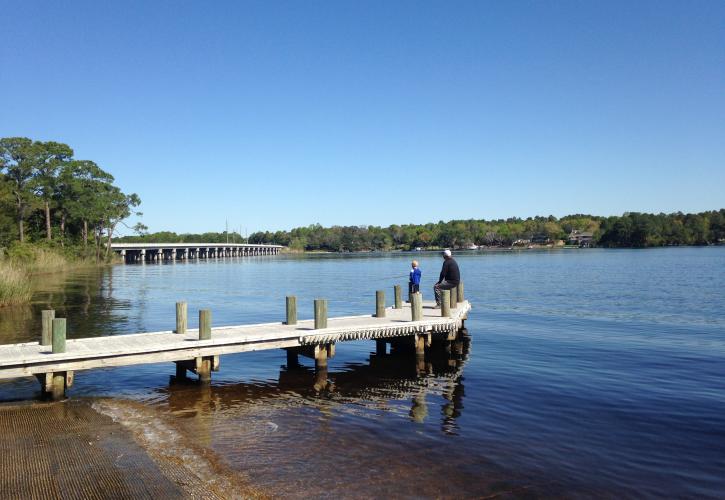 Adult and child fishing on pier.