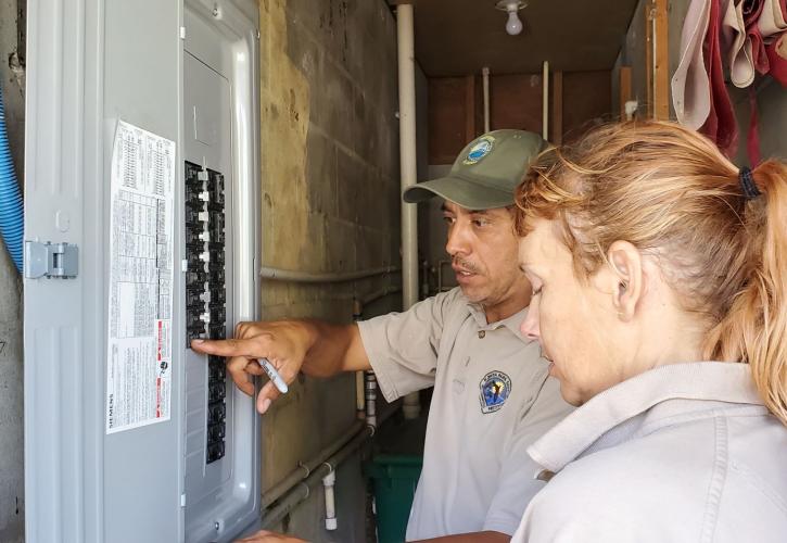 two people looking at an electrical panel