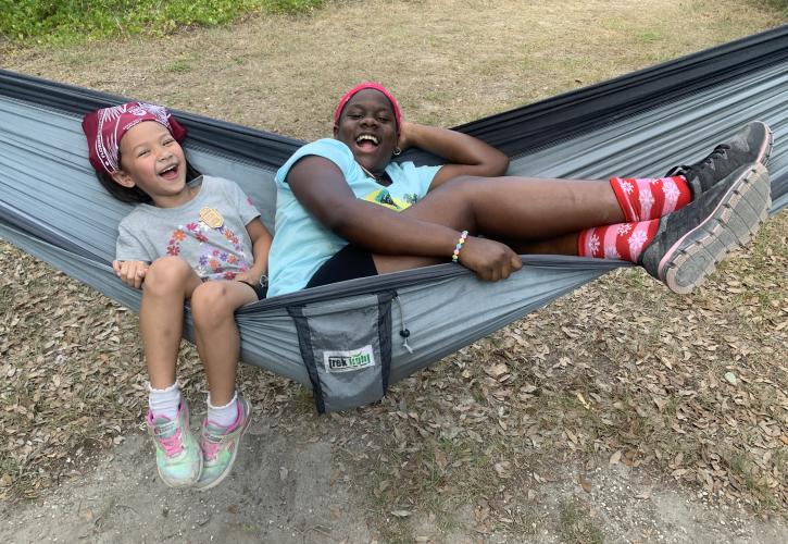 Two friends lounge in a hammock.