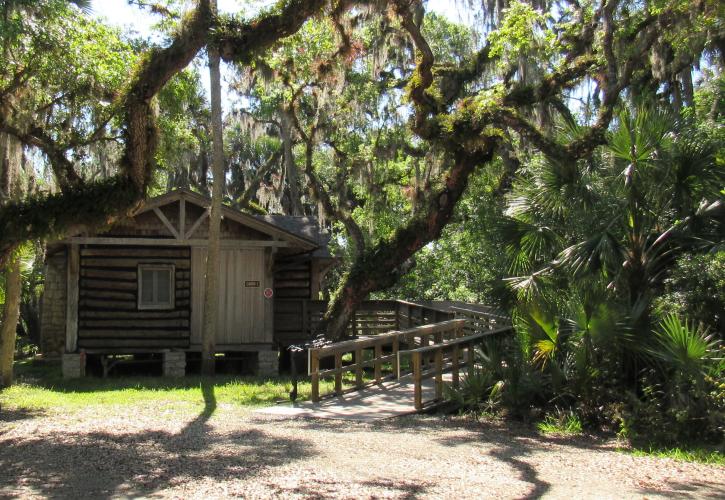 Cabin 1 is framed by Live Oak trees and has a ramp for ease of access