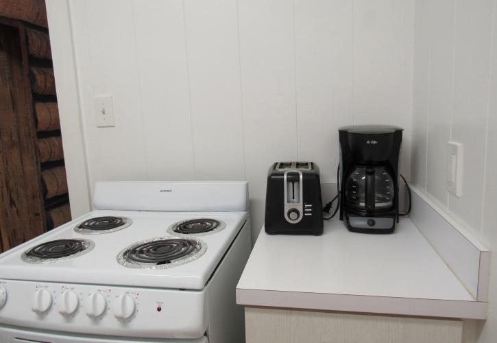 A white stove with a toaster and coffee pot in the cabin kitchen