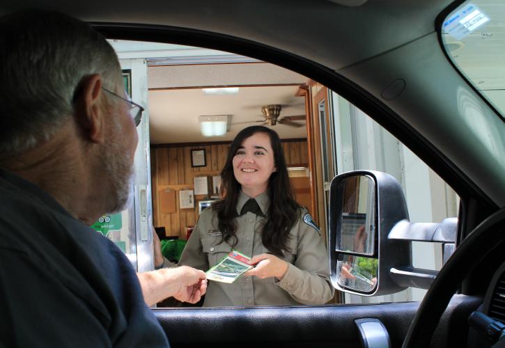Park staff at ranger station giving visitor a brochure