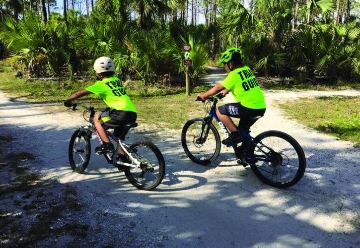 Two people wearing green shirts on a bicycle ride at Jonathan Dickinson State Park.