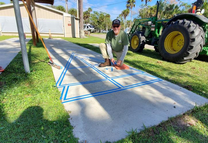 man placing painters tape on shuffle board