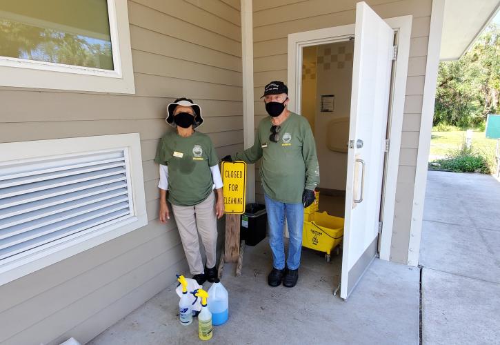 man and woman green shirts tan pants volunteers cleaning