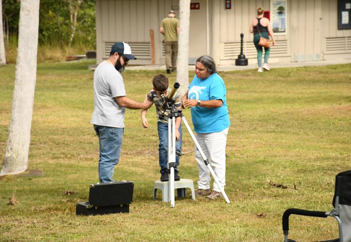 three people viewing through a solar telescope