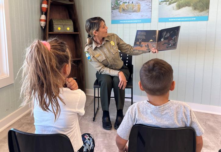 Park ranger reads a book to Junior Rangers.