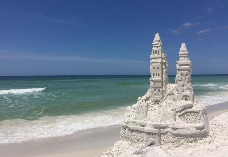 Sand castle with emerald green water in background.