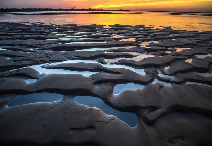 Tide pools meet a brilliant orange sunset. 