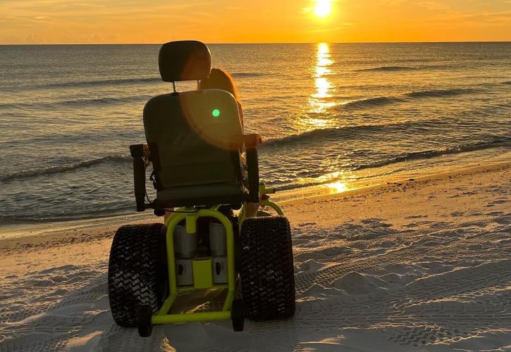 Visitor watches the sunset on the beach using a motorized beach wheelchair.